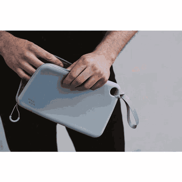a person is holding a gray via via purse
