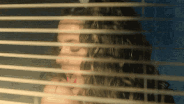 a woman 's face is visible through the blinds