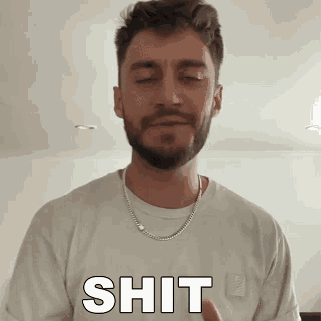 a man with a beard is wearing a white shirt with the word shit on it
