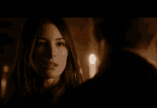 a woman is looking at a man in a dark room with candles .