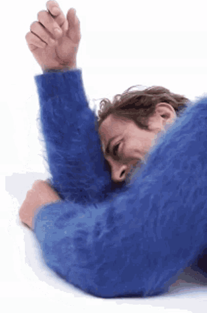 a man wearing a blue sweater is laying on the floor