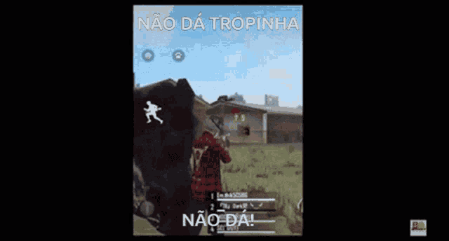 a man in a red plaid shirt is holding a gun in front of a building .