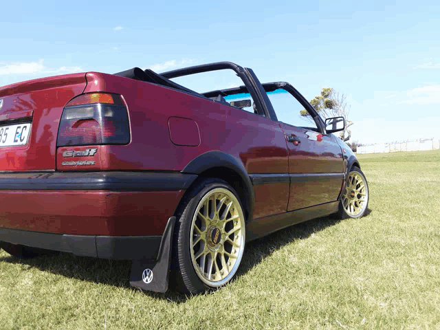 a red car with the license plate 95 ec is parked in the grass