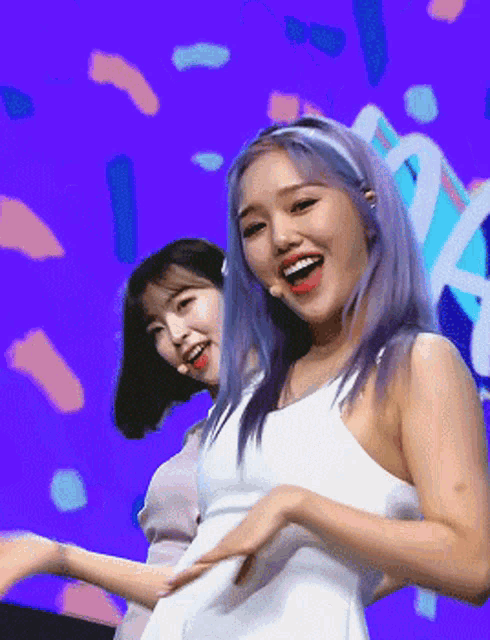 two women are dancing in front of a purple background with the letter a in the middle