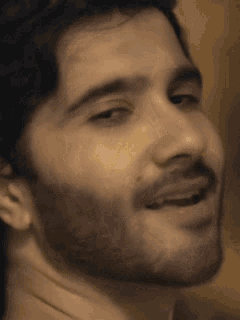 a close up of a man 's face with a beard smiling