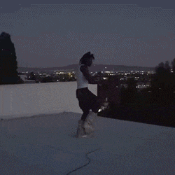 a person is running on a rooftop at night with a city in the background