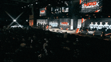 a group of people standing on a stage in front of a large screen that says shock on it