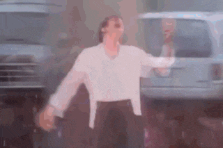 a man in a white shirt and black pants is standing in front of a white van .