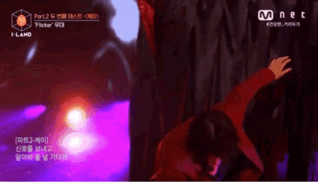 a man in a red jacket is dancing on a stage with a mnet logo in the corner