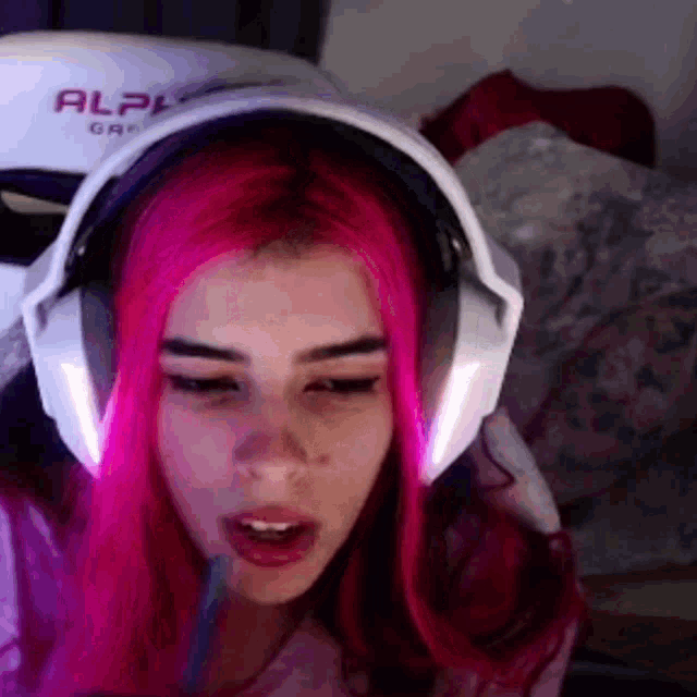 a girl with pink hair is wearing headphones while playing a video game .