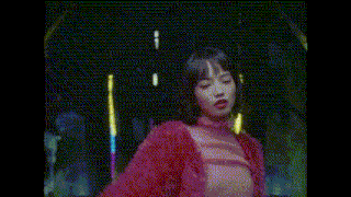 a woman wearing a pink fur coat is standing in the rain at night .