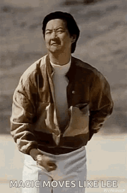 a man in a brown jacket and white shorts is holding a tennis racquet and making a funny face .