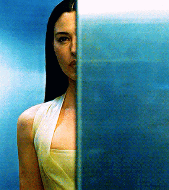 a woman in a yellow dress is behind a blue glass
