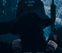 a person wearing a black bucket hat that says g-sharks on it