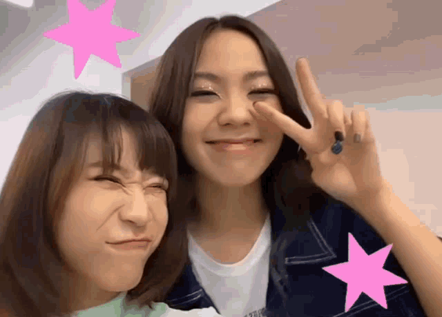 two girls are posing for a picture and one of them has a tattoo on her finger