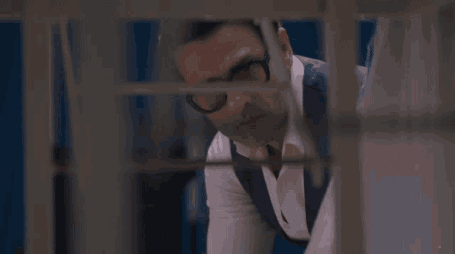 a man with glasses is looking through a fence