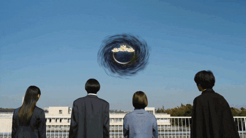 a group of people are standing on a balcony looking up at a circle in the sky