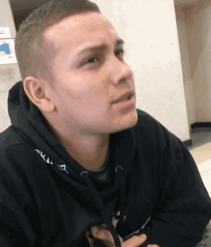 a young man wearing a black hoodie with the letter a on the front