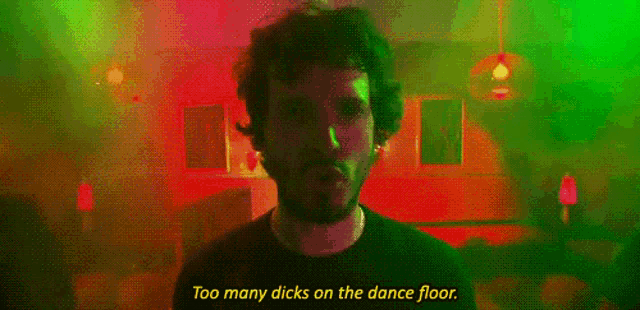 a man is standing in front of a green light with the words " too many dicks on the dance floor "