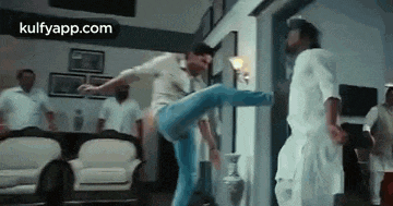 a man is kicking another man in the face while a group of men watch .
