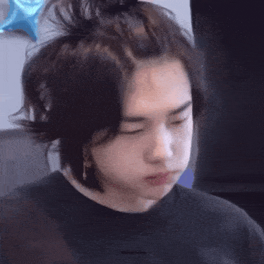 a close up of a person 's face with their eyes closed and a messy bun .