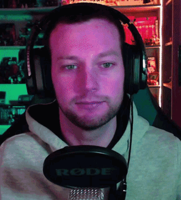a man wearing headphones stands in front of a rode brand microphone