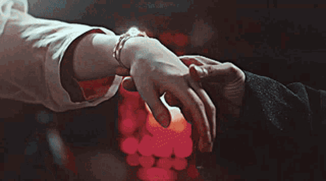 a man and woman holding hands in front of a candle