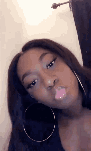 a woman wearing hoop earrings is making a funny face .