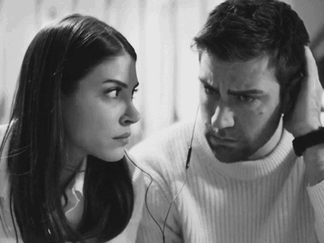 a man and a woman looking at each other with headphones on