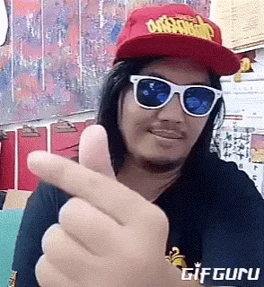 a man wearing sunglasses and a red hat is making a heart shape with his finger