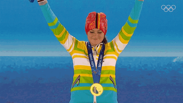 a woman in a striped jacket holds up a medal that says usa