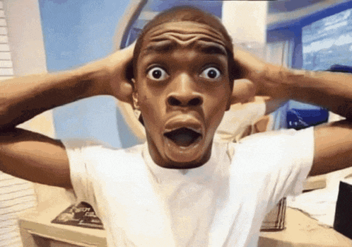 a man in a white shirt is making a surprised face with his hands on his head
