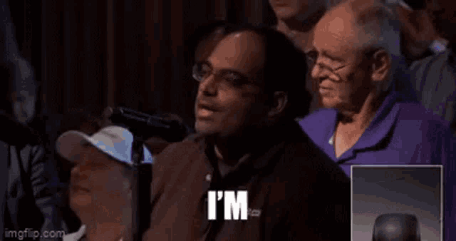 a man is sitting in front of a microphone with the word supergenius written on his face