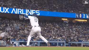 a baseball player is swinging at a ball in front of a banner for ux airlines