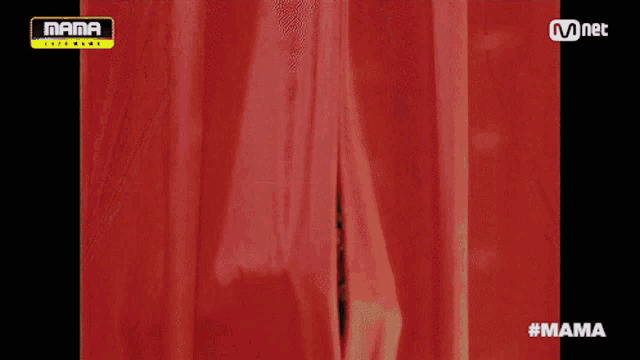 a man in a sequined jacket is behind a red curtain with a mama logo on it