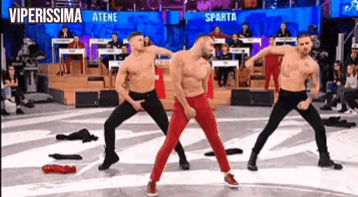 three men without shirts are dancing on a stage in front of a large screen that says viperissima