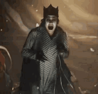 a man in a clown costume is screaming and holding a microphone in a dark room .