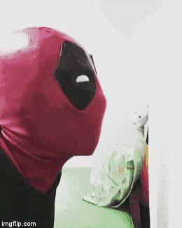 a person wearing a deadpool costume is standing next to a green pillow .