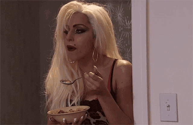 a woman with blonde hair is eating cereal from a bowl with a spoon