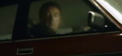 a person is sitting in a car with their head out the window .