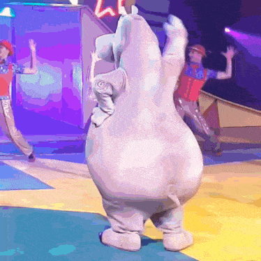 a man in a red hat is standing next to a hippo costume