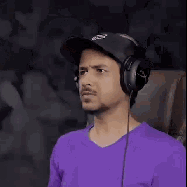 a man wearing headphones and a baseball cap is sitting in a chair .