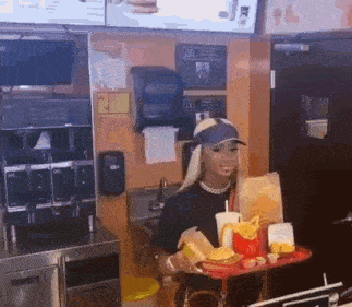 a woman is holding a tray of hamburgers and french fries in a mcdonald 's restaurant .