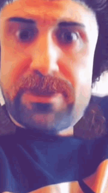a man with a beard and mustache is looking at the camera and making a funny face .
