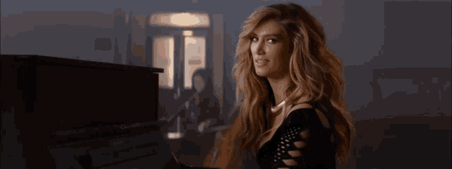 a woman in a black dress is playing a piano in a dark room