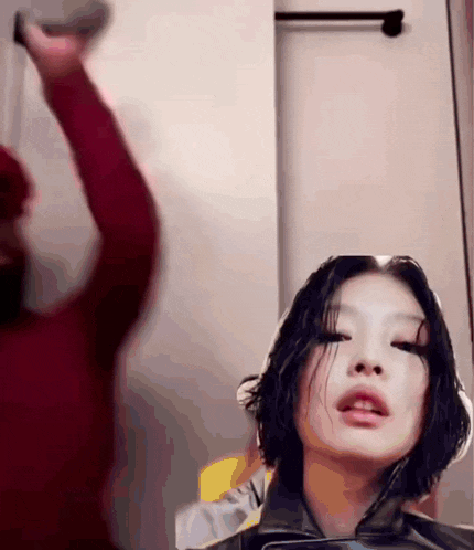 a woman in a red sweater is getting her hair cut