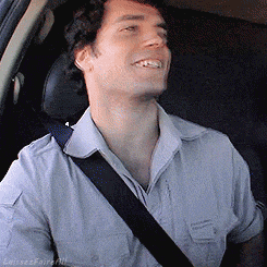 a man wearing a blue shirt and a black seat belt is smiling