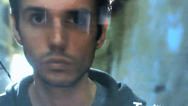 a close up of a man 's face with the letter t on the bottom left