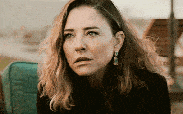 a woman with a serious look on her face wears earrings