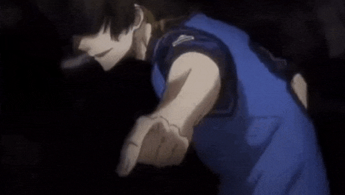 a man in a blue shirt is pointing his finger at the camera in a dark room .